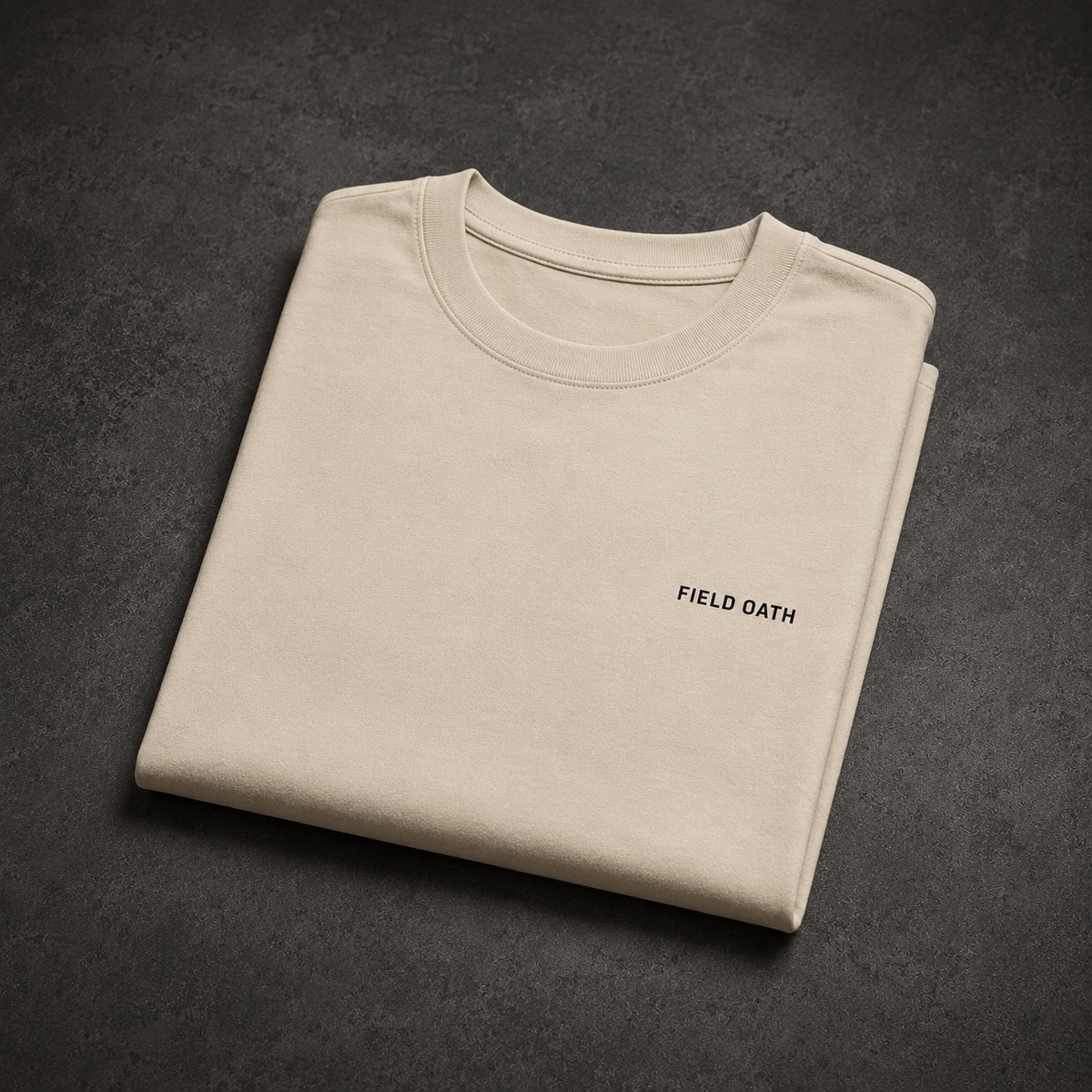Bone FIELD OATH Crest Line T-Shirt folded on a dark concrete studio table